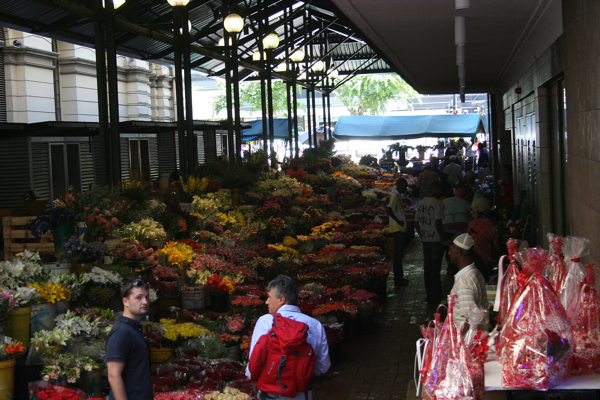 Flower sellers’ stalls on Adderley Street, Cape Town: cut flowers and greenery standing in buckets along the pavement.