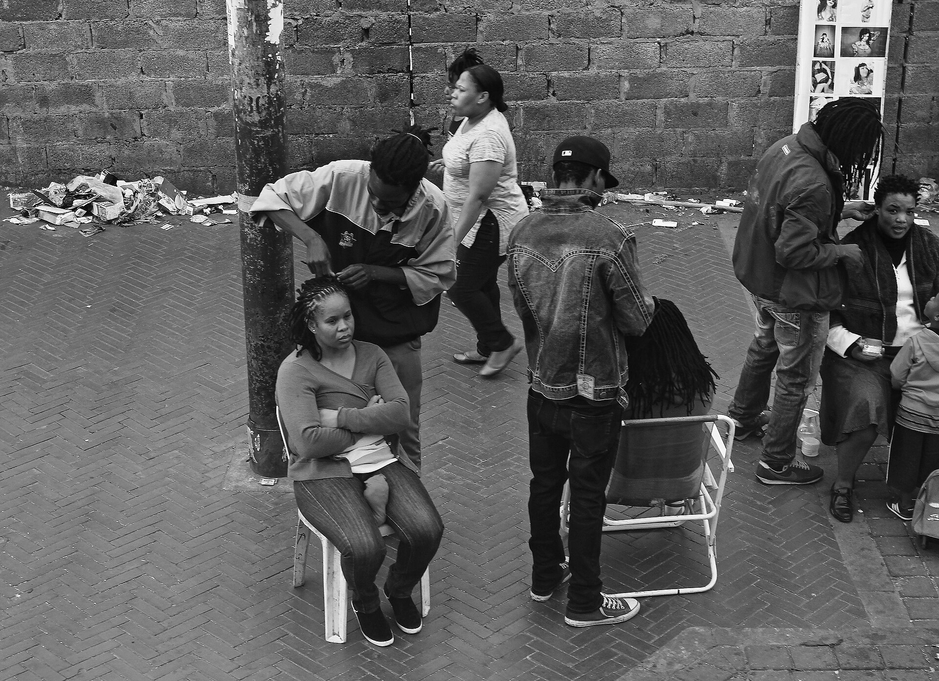 A black and white photograph of the interior of an informal hair salon in Yeoville, Johannesburg.